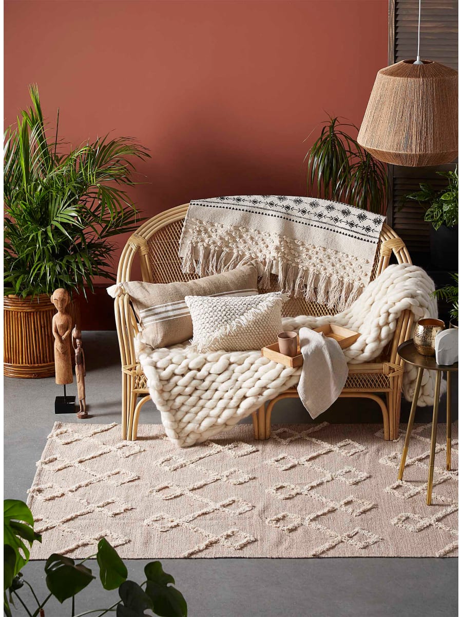 Wicker chair with cushions and blanket draping over