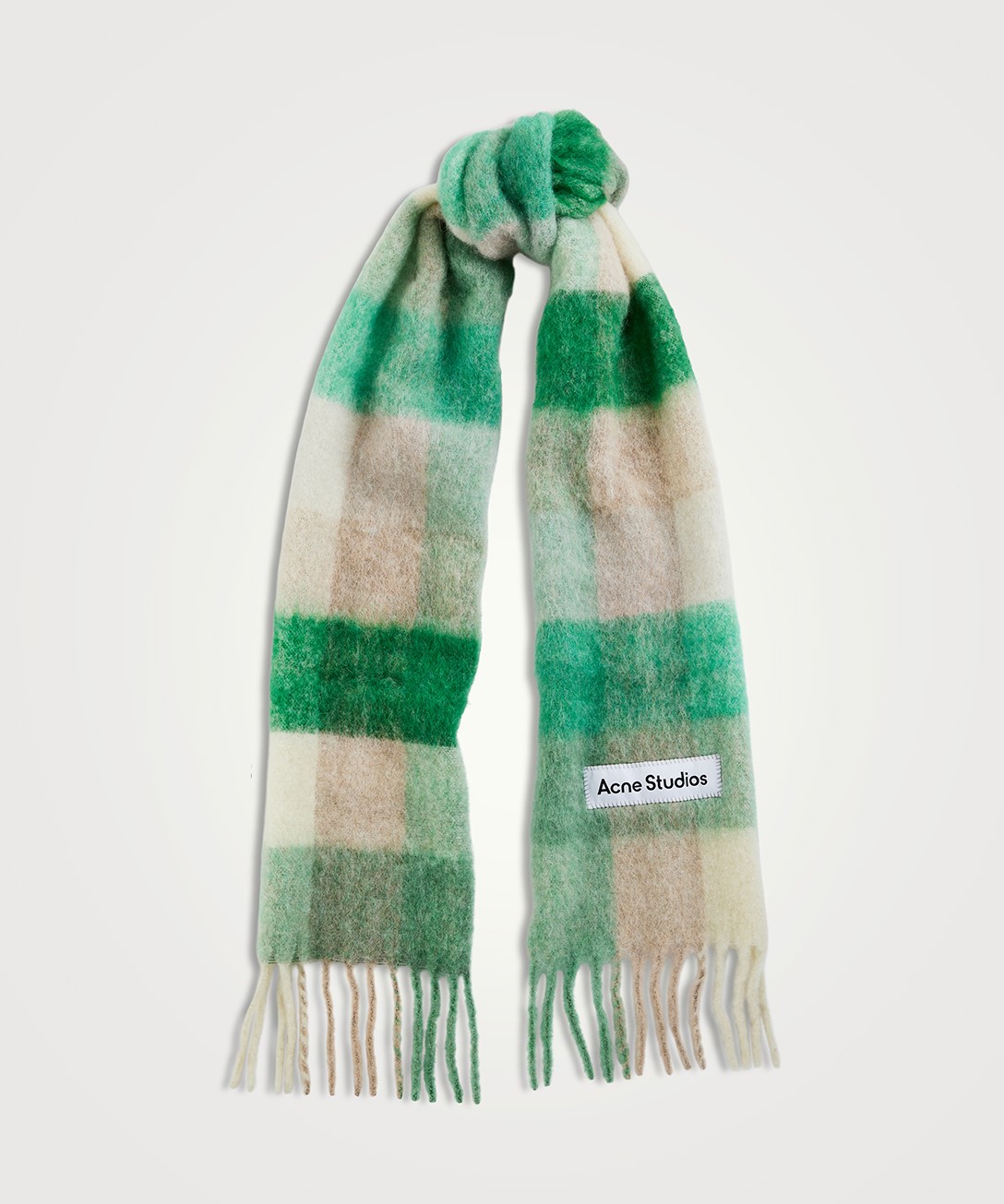 Image of a checkered print Acne studios scarf. There is fringe detailing and a label reading "Acne Studios." The scarf is in various shades of grey, cream and green.