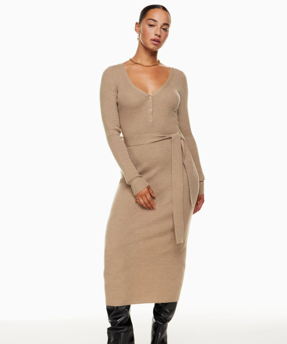 Image of a model wearing a tan knit dress from Aritzia. It has a soft V-neck, a tie belt and three buttons.