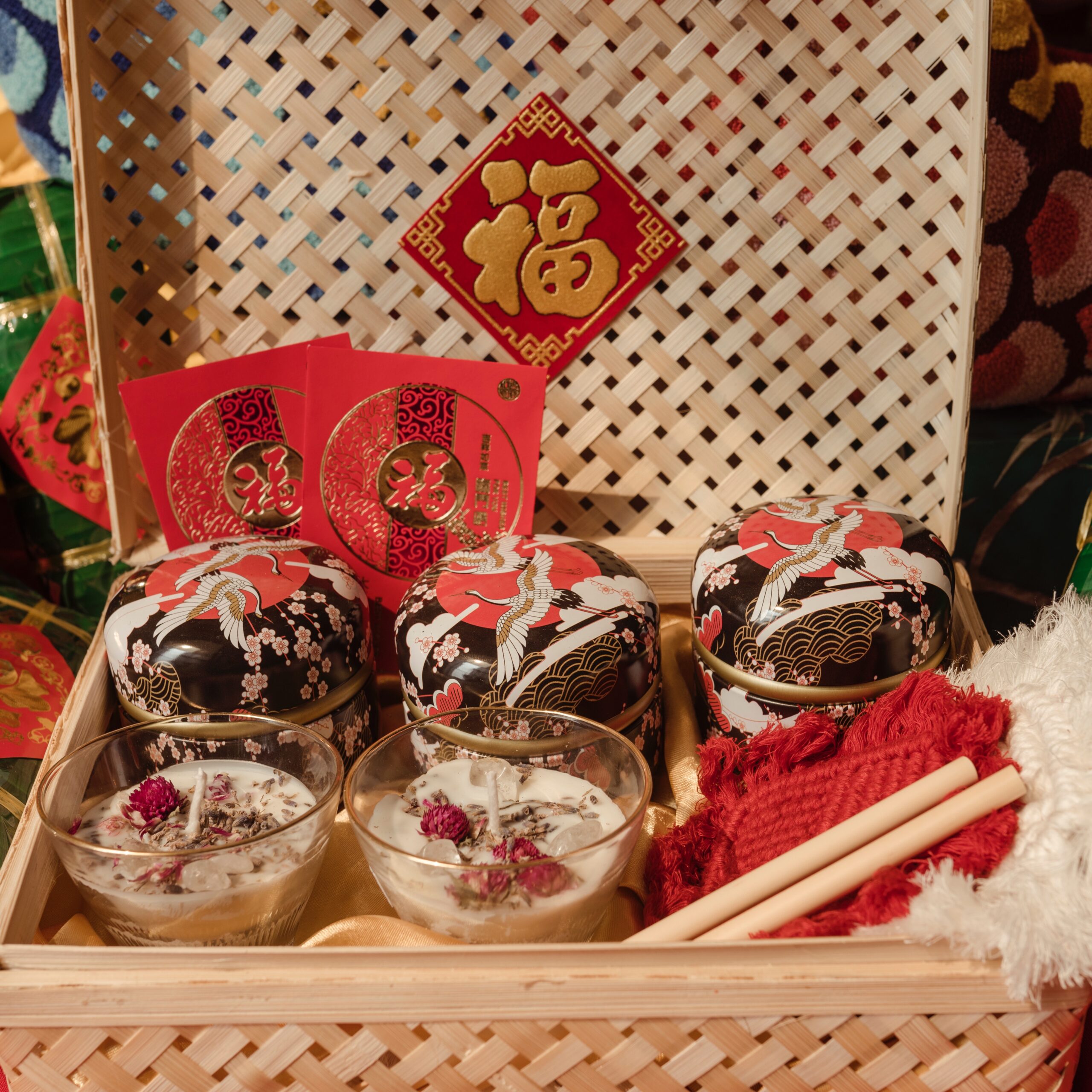 Image of a Lunar New Year gift set in a wicker box consisting of red envelopes, treats and decor.