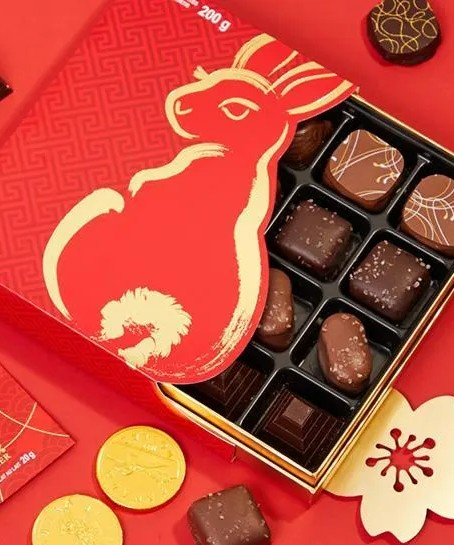 Image of a box of assorted chocolates. The front of the box is red with a gold bunny.