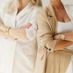 2 women in neutral blazers and gold jewelry