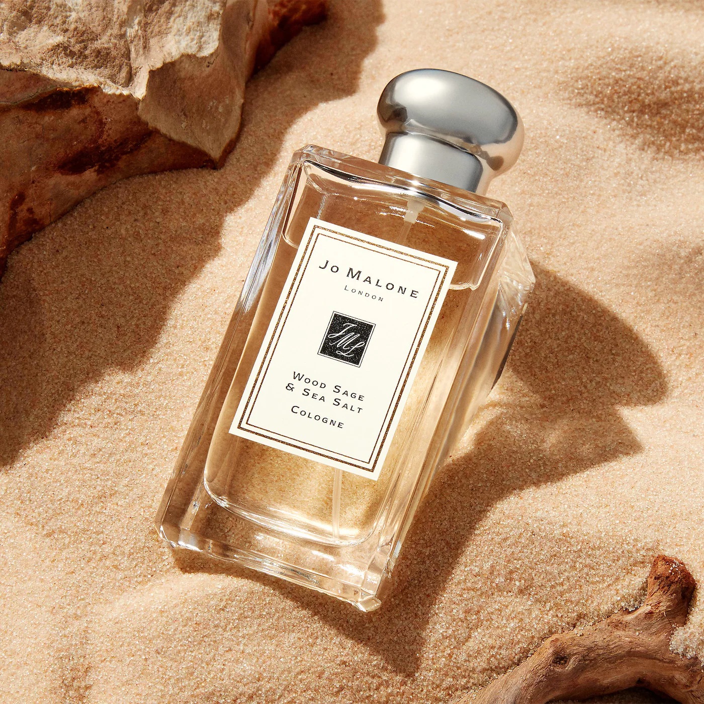 Perfume bottle with white label perched in the sand.