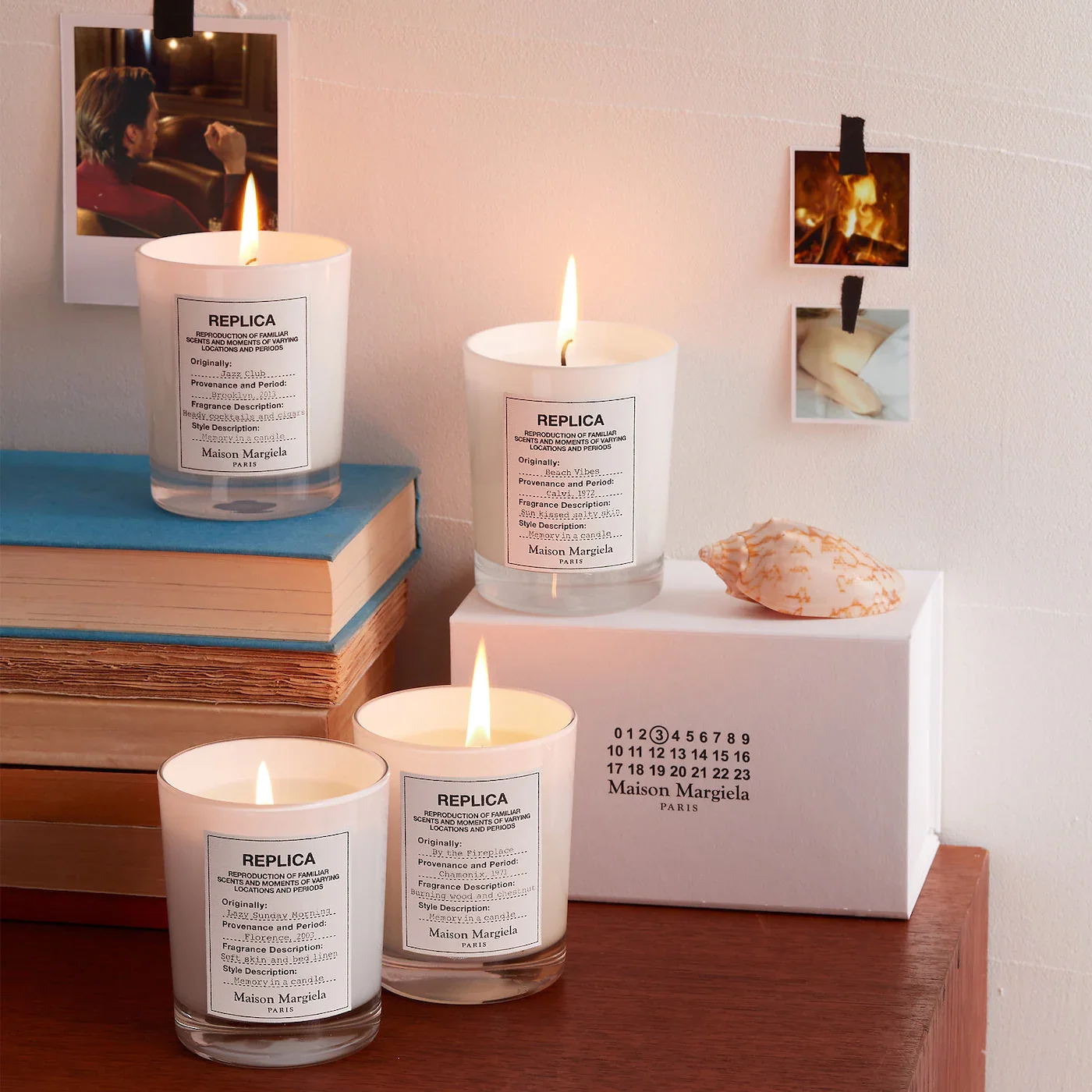 Four white candles sitting on various books and surfaces with polaroid pictures behind it.