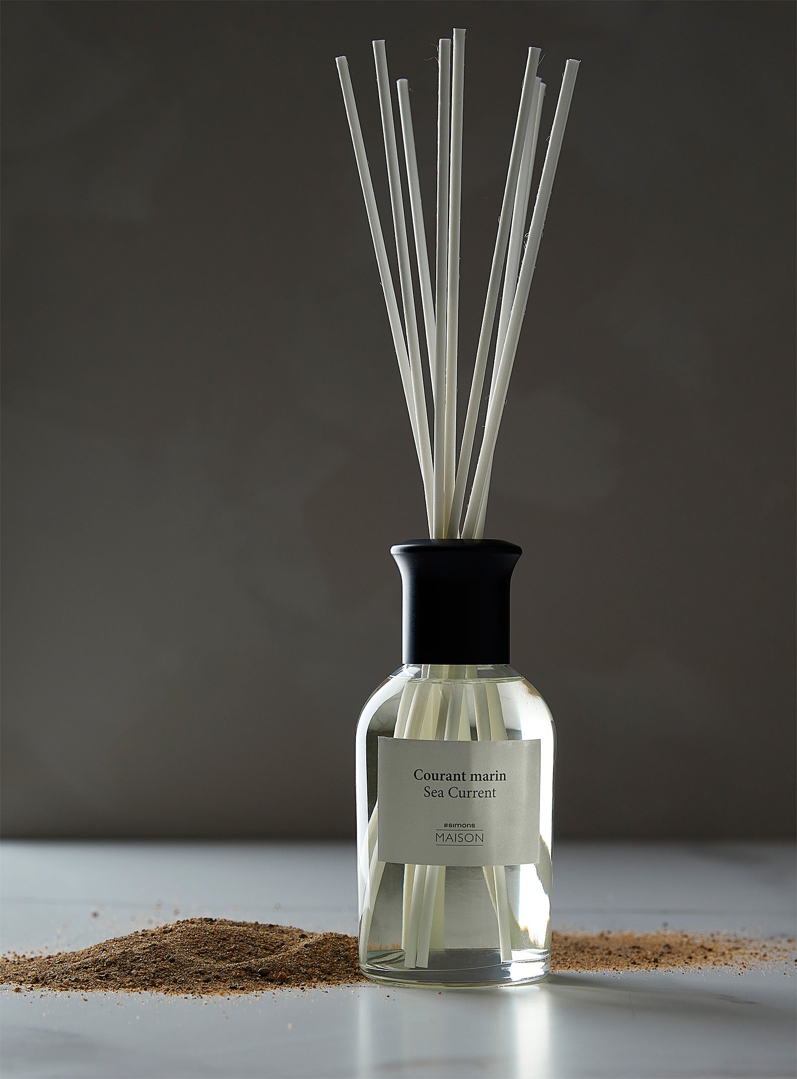 Essential oils from Simons with sticks on white surface.