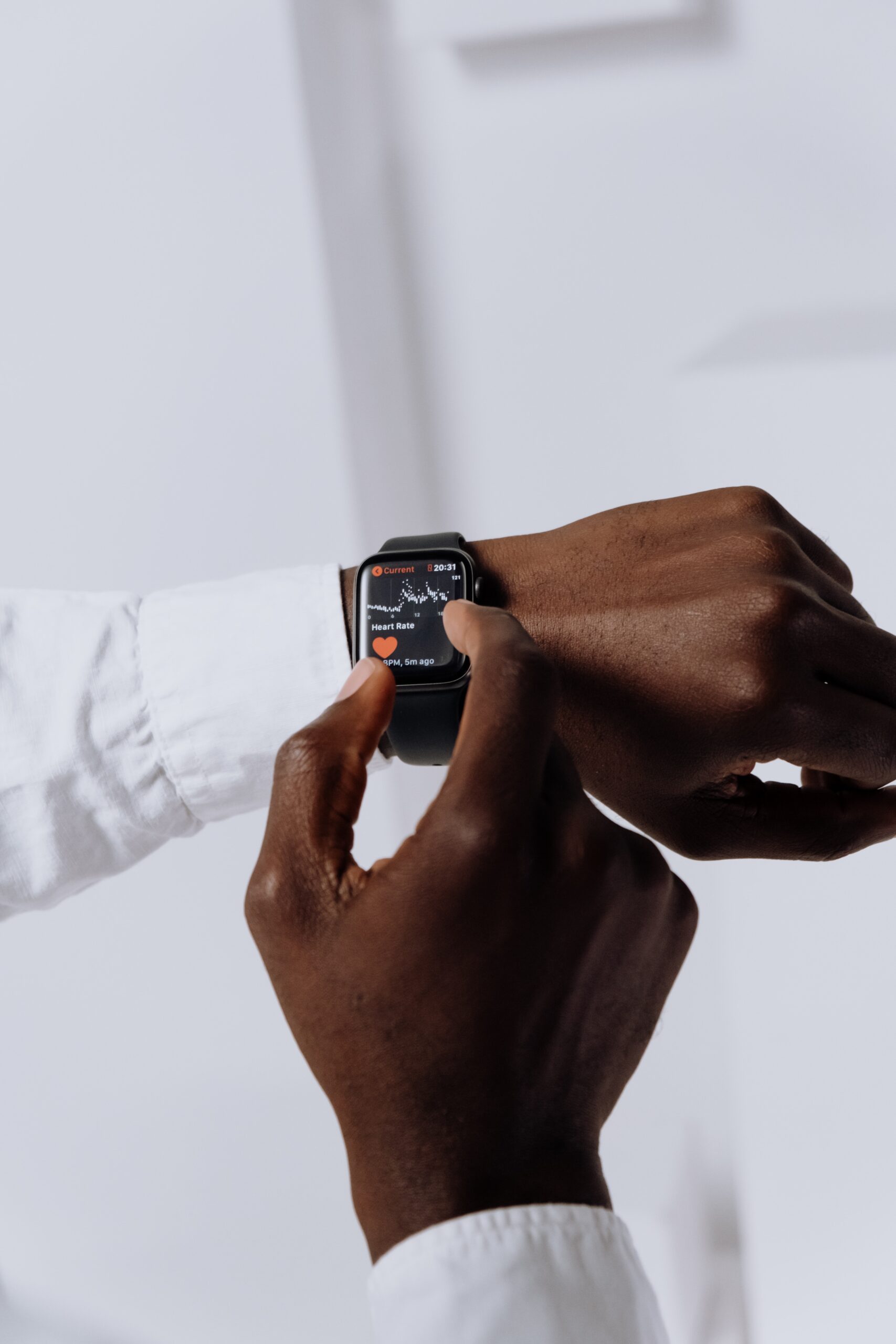 Close up image of an Apple watch on a person's left wrist. The cuff of a white dress shirt is visible. The person's right hand is adjusting the watch.