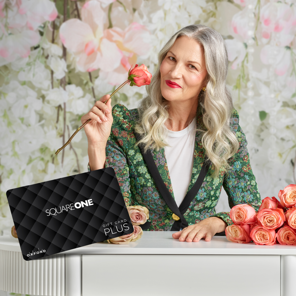 Woman holding roses posing with a gift card from Square One