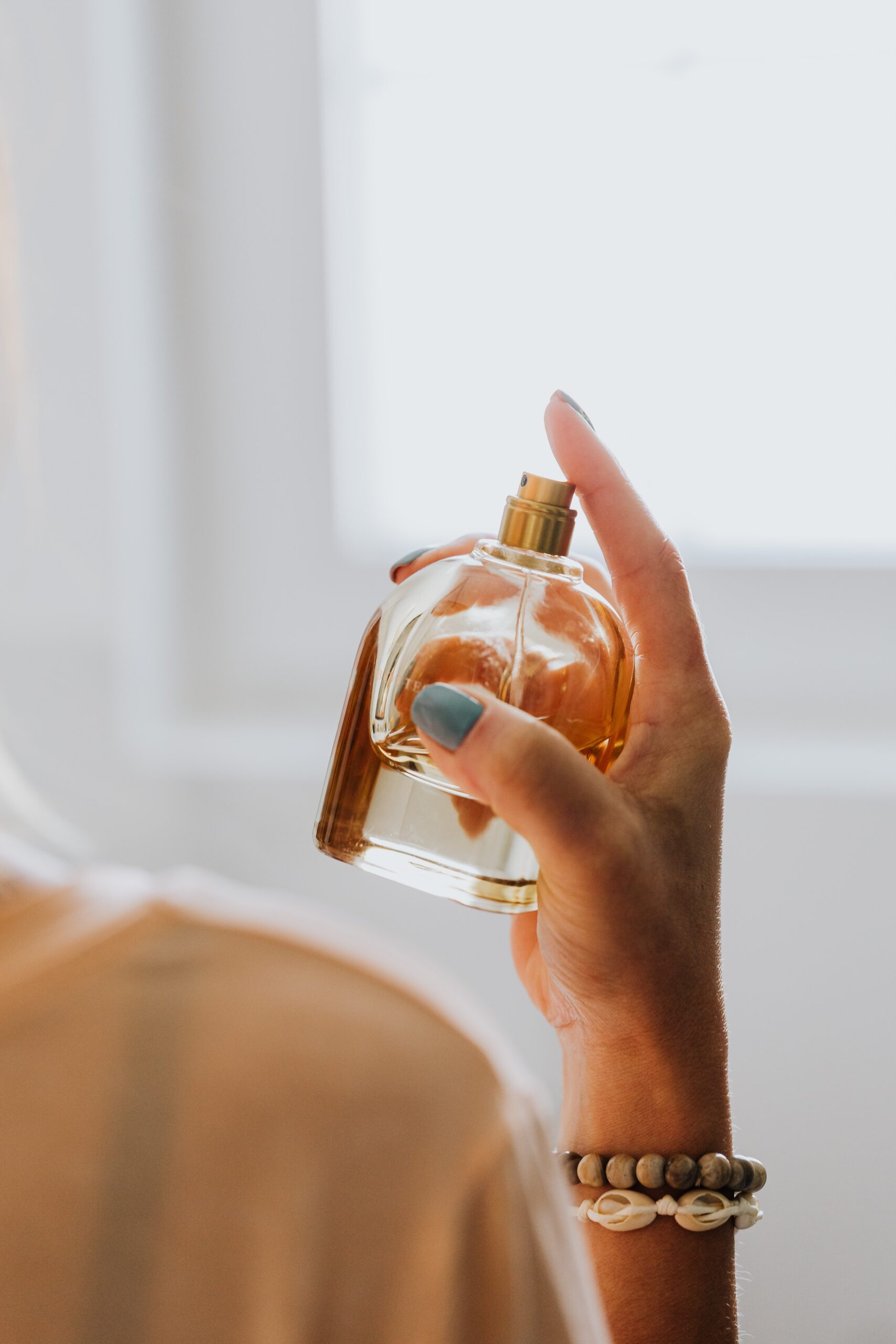 Model spraying bottle of perfume on herself.