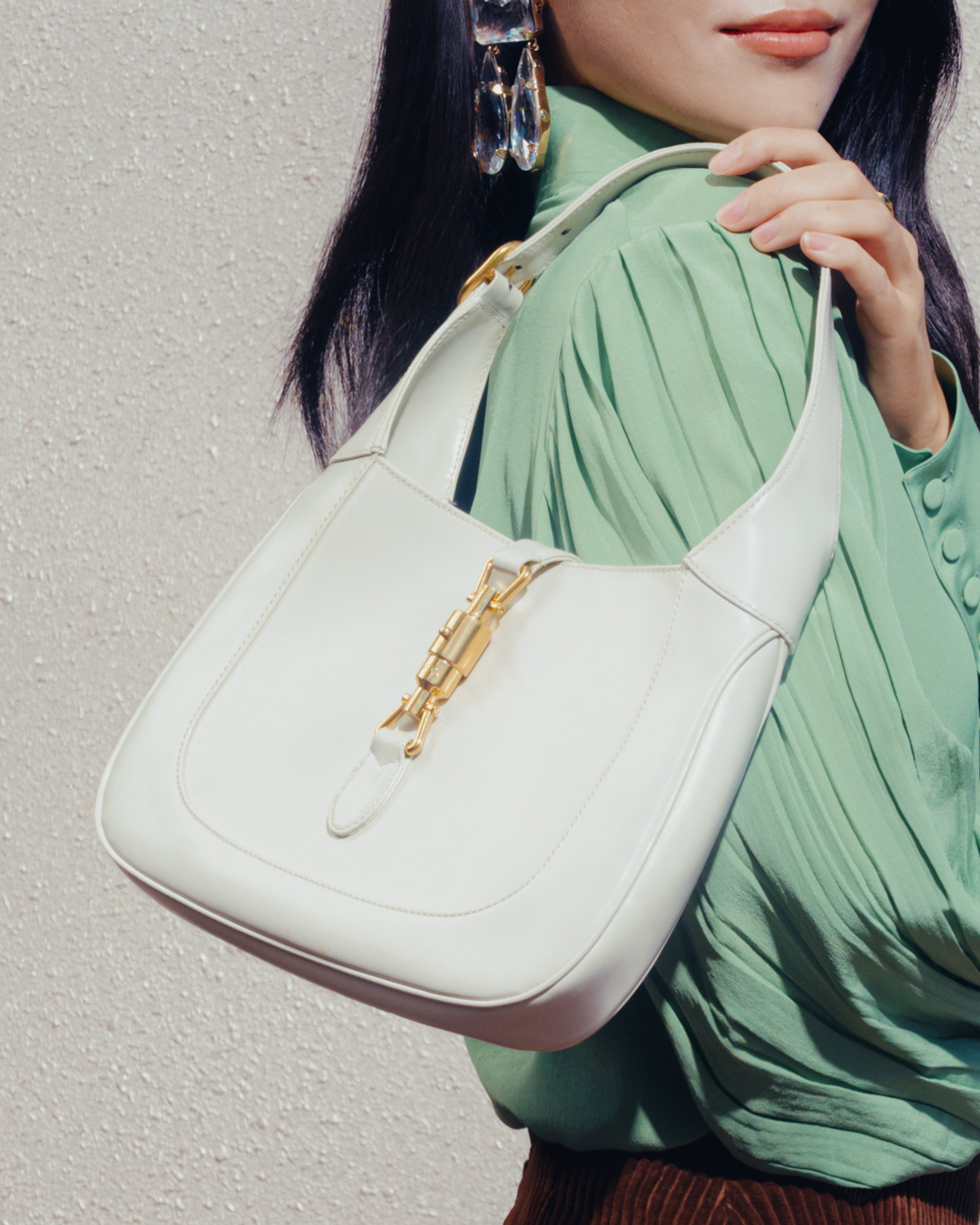 image of a woman posing with a white gucci jackie handbag