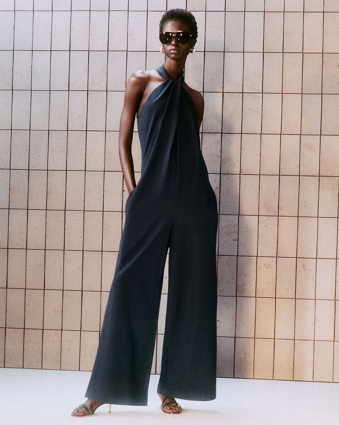 Image of a model wearing a black jumpsuit with wide legs and a halter top