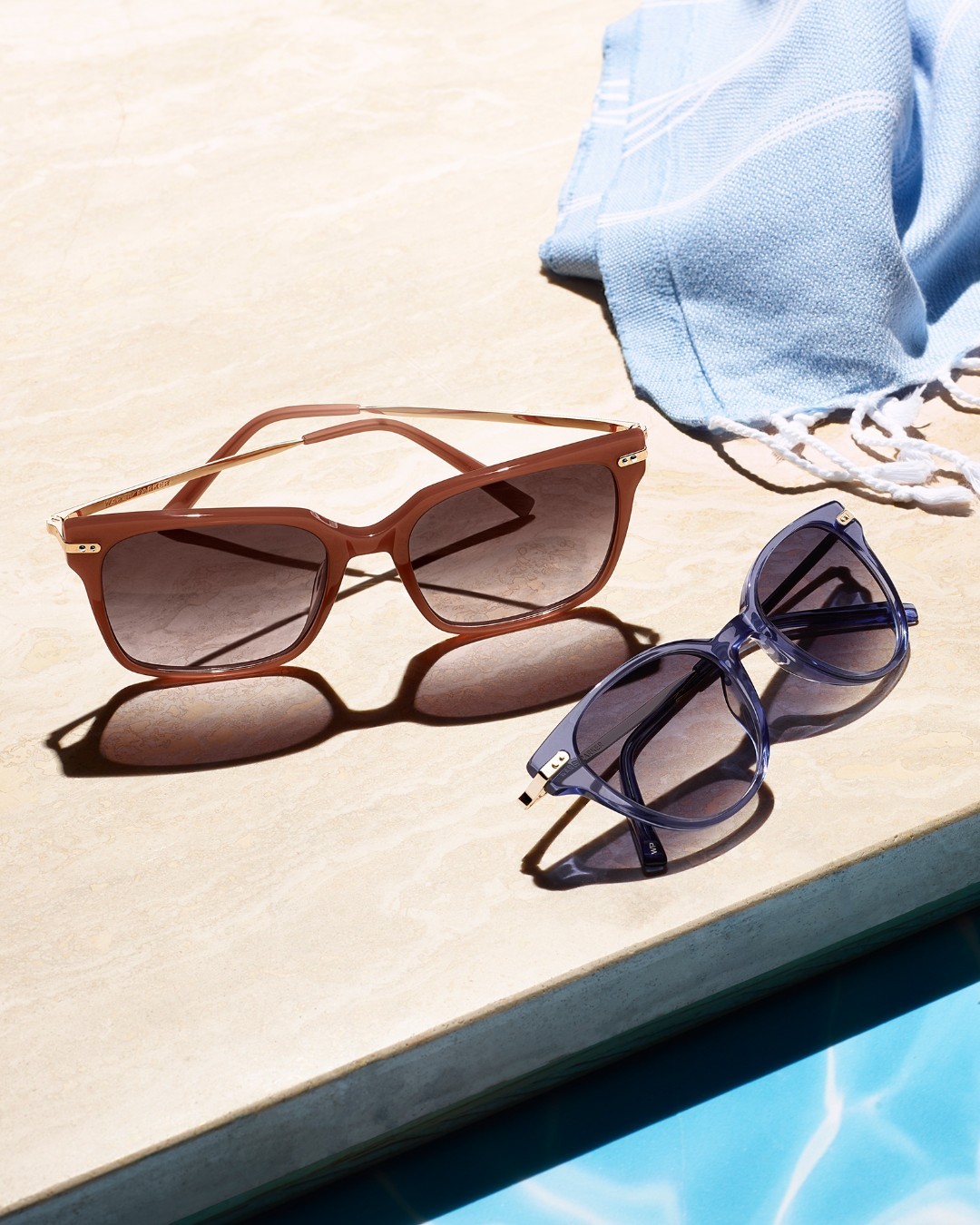 lifestyle image of two pairs of sunglasses in a pool scene. one pair is brown, the other is blue