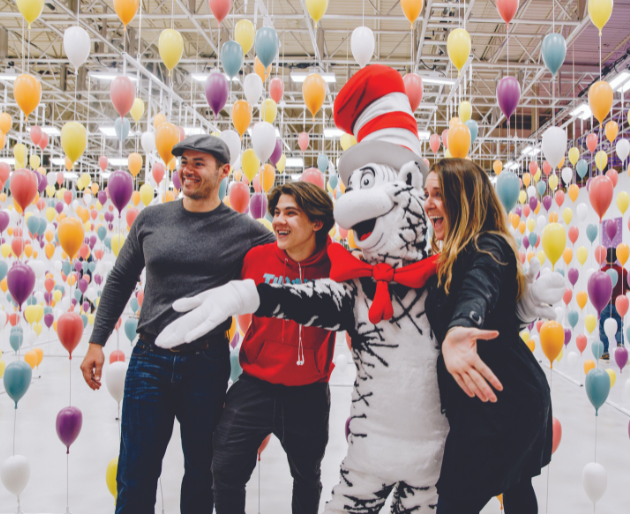 Dr Seuss costumed character posing with 2 guys & a girl