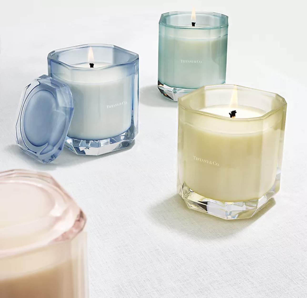 Several candles in coloured glass containers from Tiffany & Co. Holt Renfrew