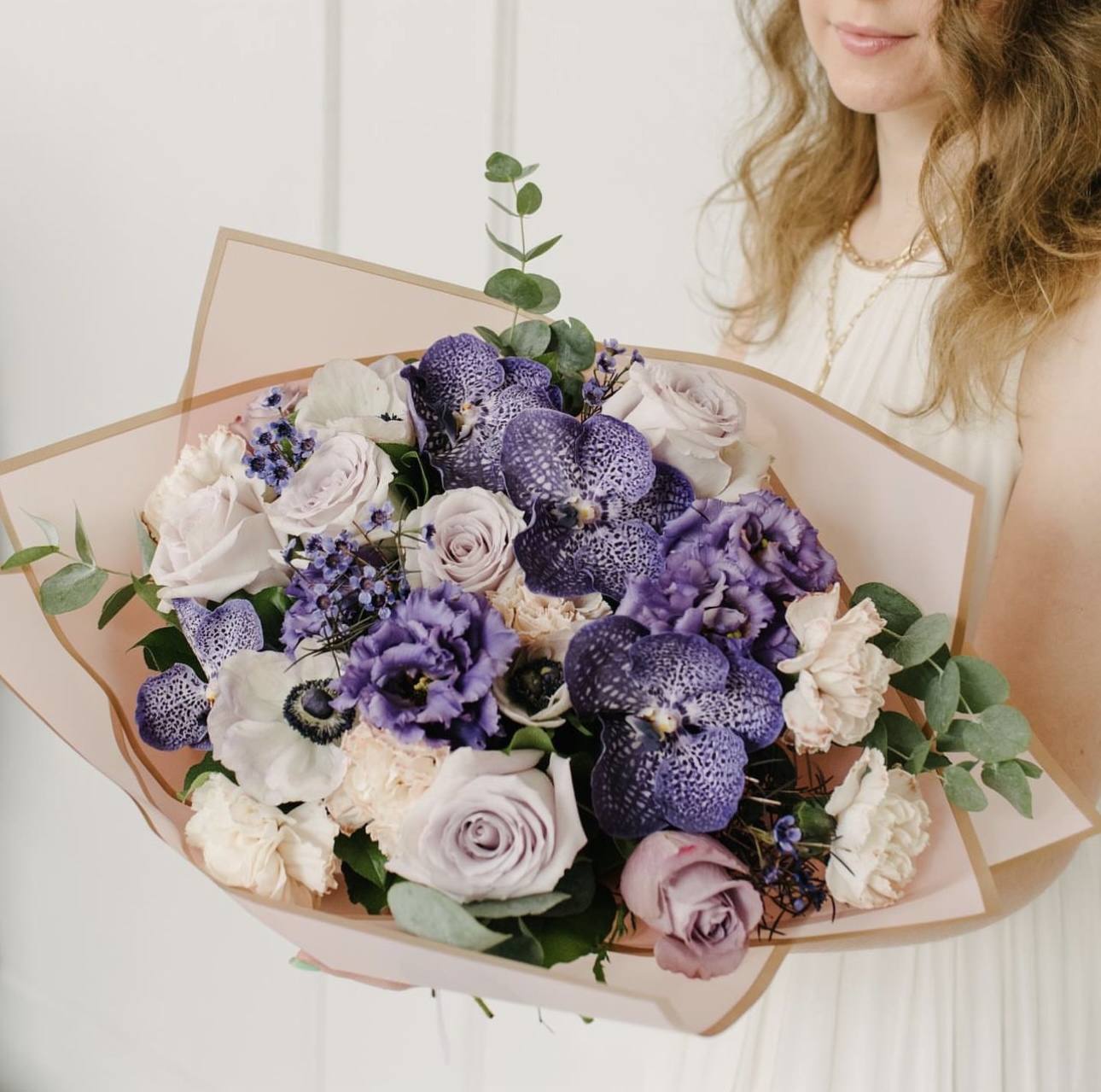 A woman holding a bouquet of purple and white flowers from Blossom Moments