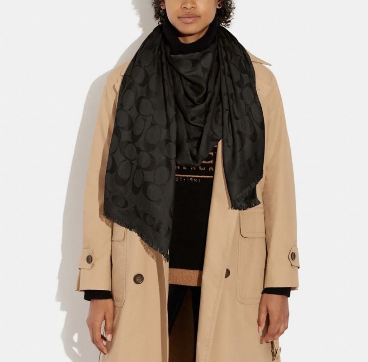 A person wearing a black Coach scarf and a beige trench coat