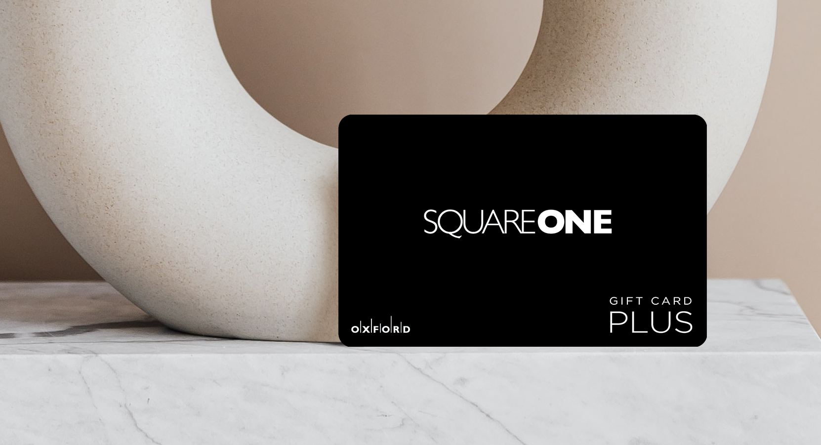 promotional image of a black square one gift card in front of an oval ceramic vase