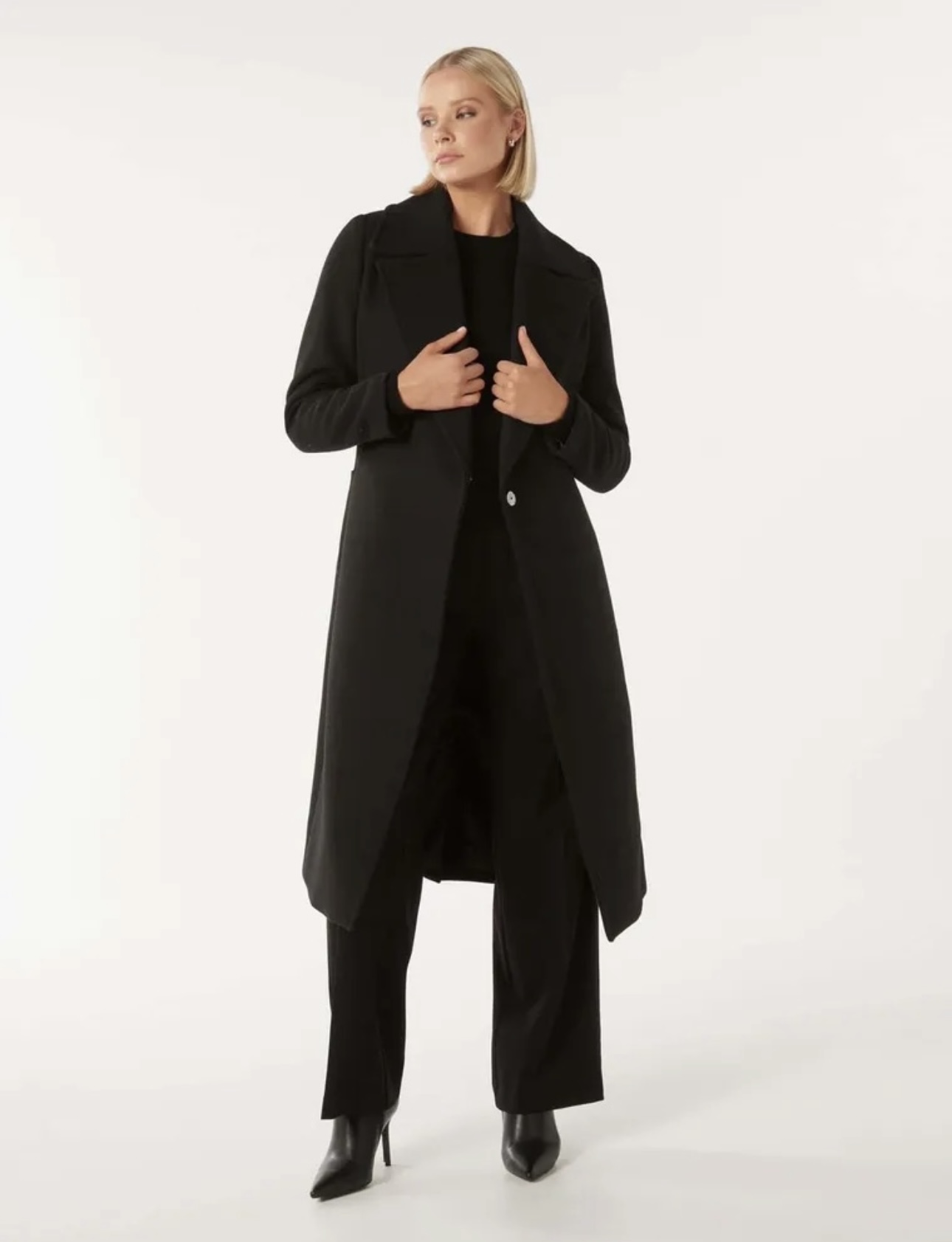 Woman wearing a long black coat, black dress pants and black high heels