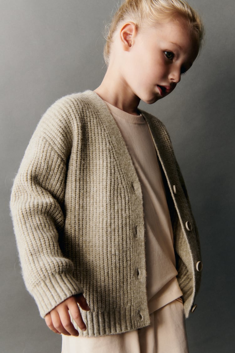 A child wearing a beige coloured knit cardigan