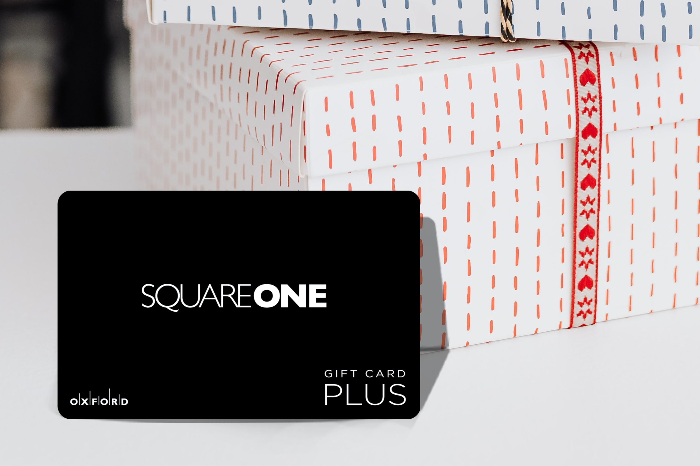 promotional image of a black square one gift card perched in front of gift boxes