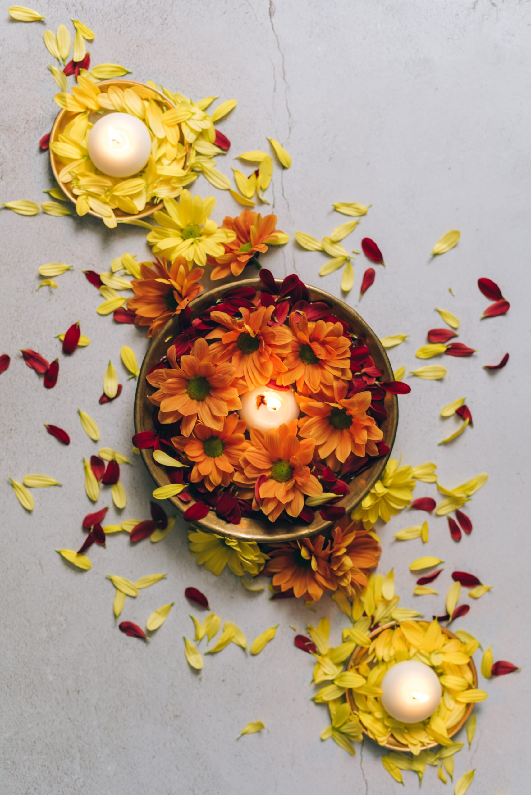 Three candles in bowls surrounded by flower petals
