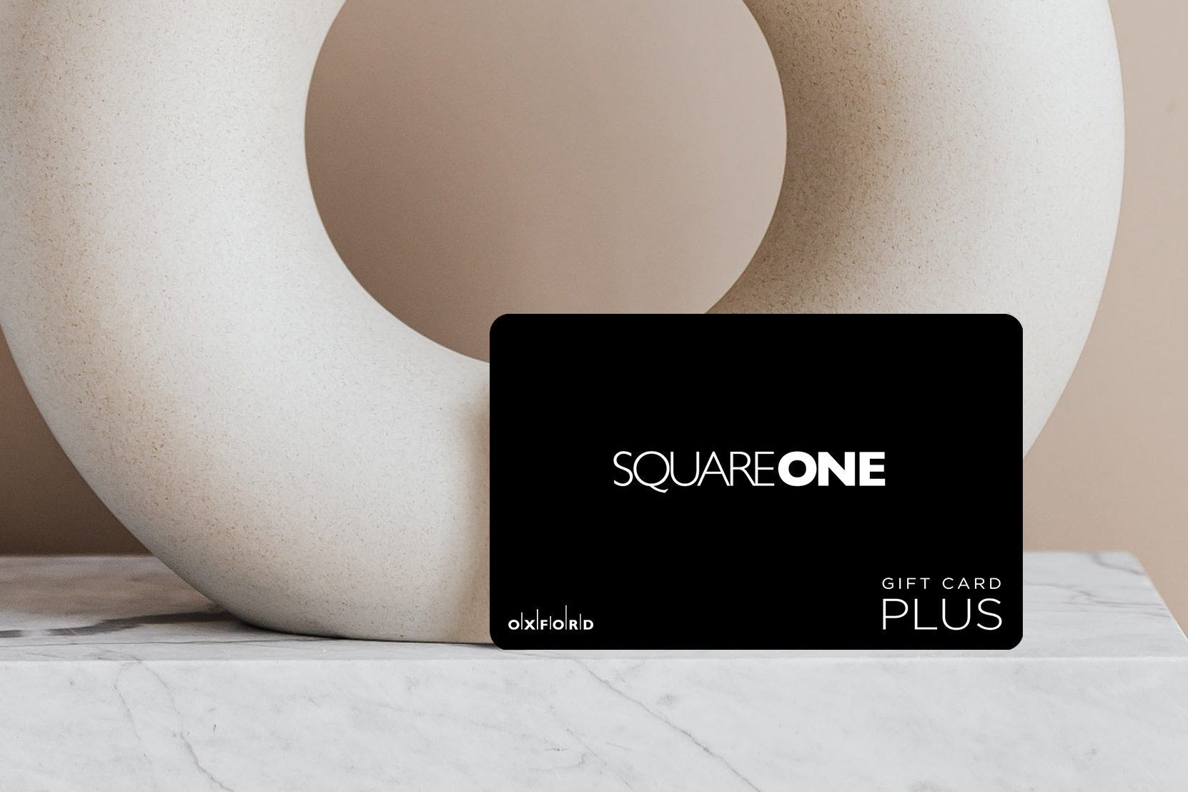 promotional image of a black square one gift card in front of a neutral circular vase