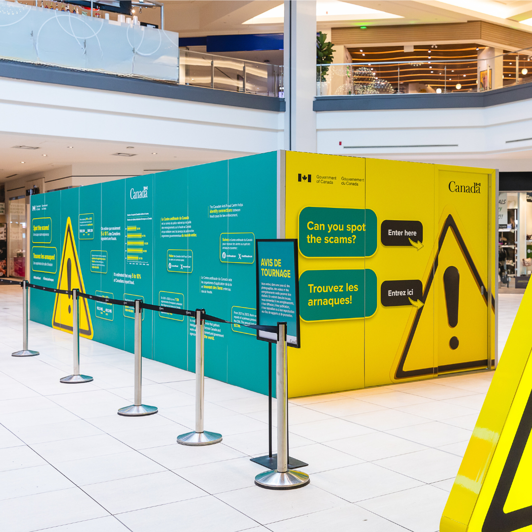 A row of stanchions in front of an activation with a yellow caution sign