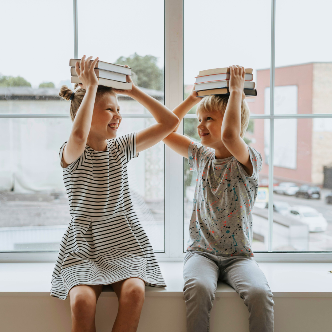 Two children holding books on their head