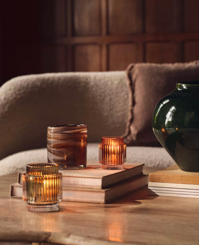 Some lit candles and a stack of books on a coffee table