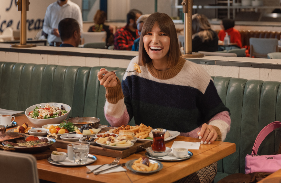 A woman laughing and eating at a restaurant table.