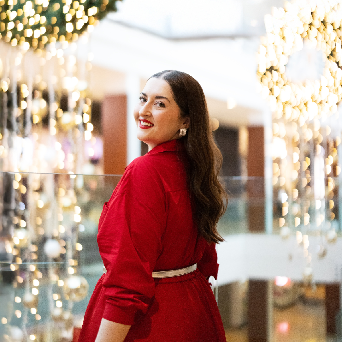 A woman looking over her shoulder with Christmas decor hanging in the background