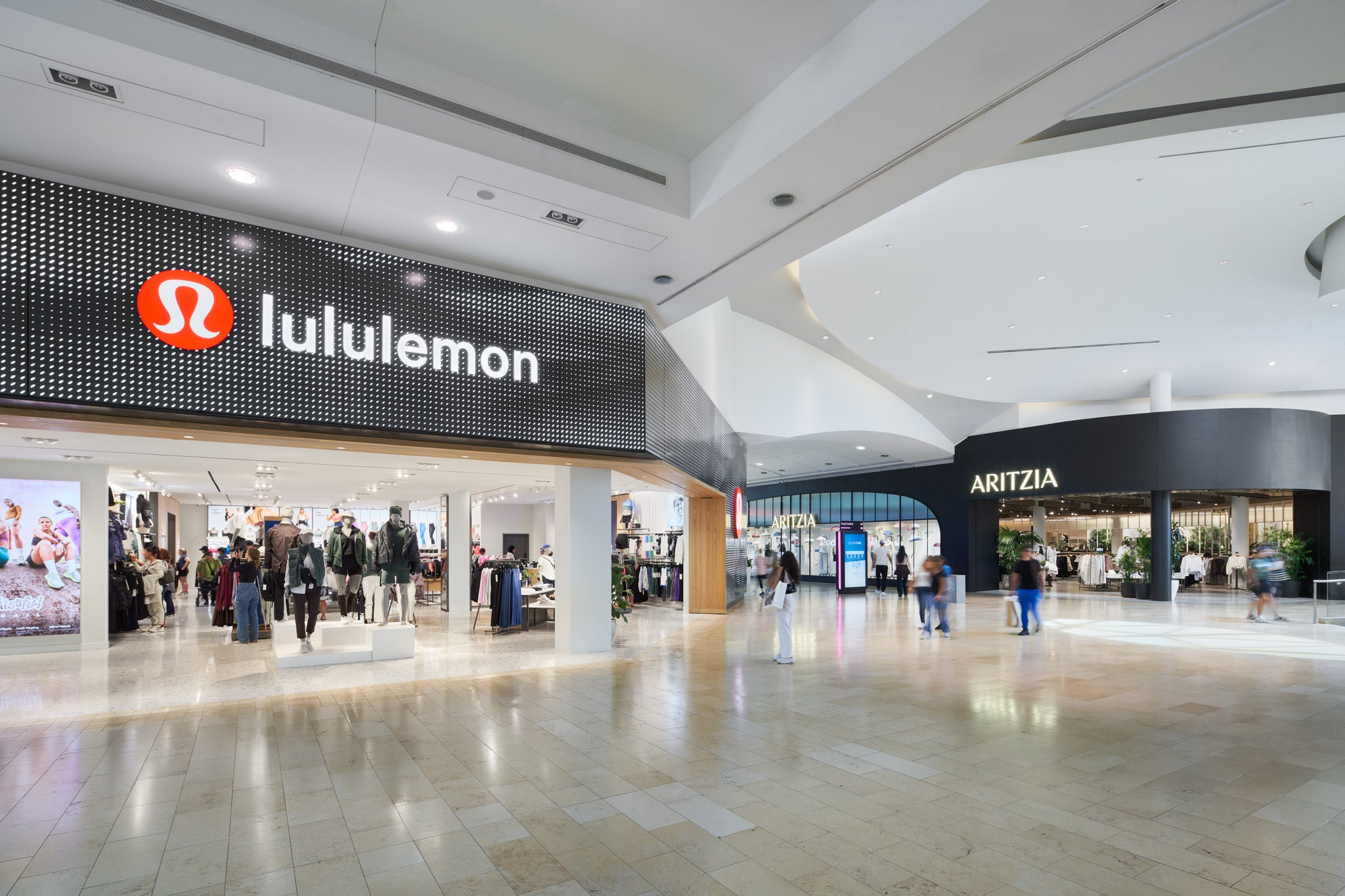 The hallways of a shopping centre featuring the storefronts of lululemon and Aritzia