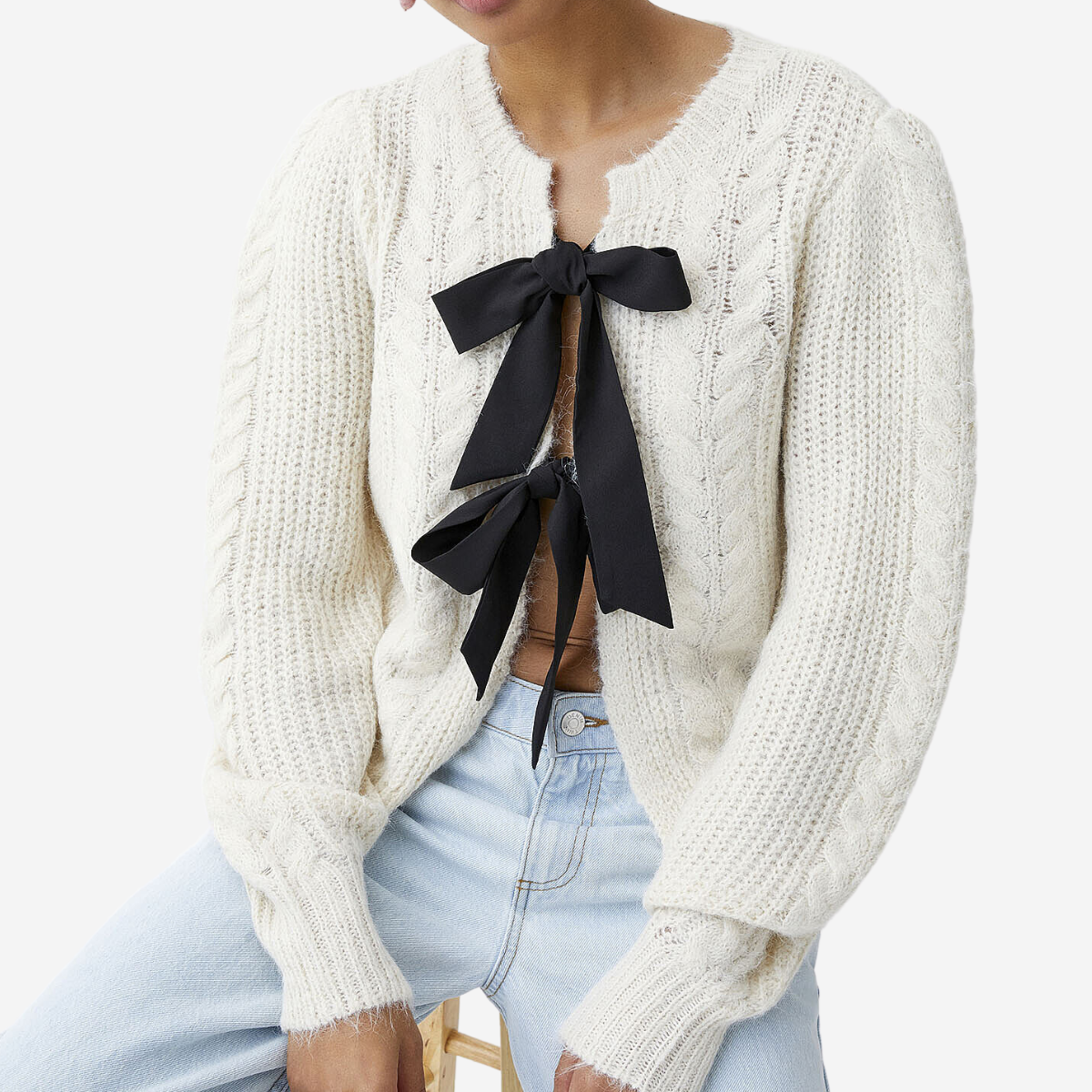 A white cardigan with a black bow on the front