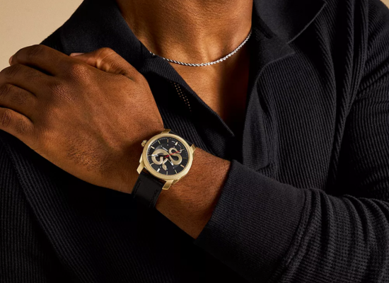 A man wearing a gold accented watch with a snake design on the face.