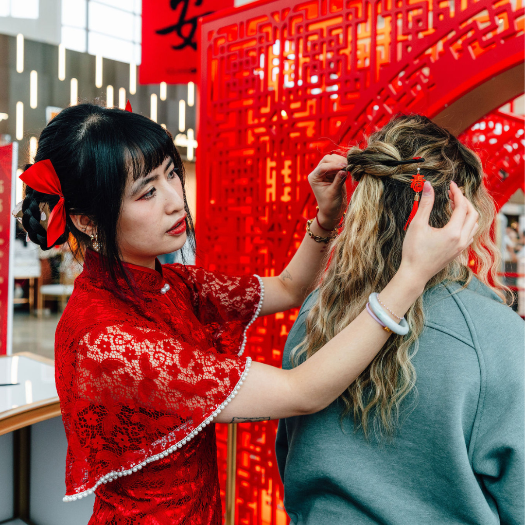 A woman styling another woman's hair.