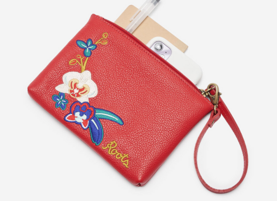 A red leather wristlet with a floral motif pattern stitched on it.