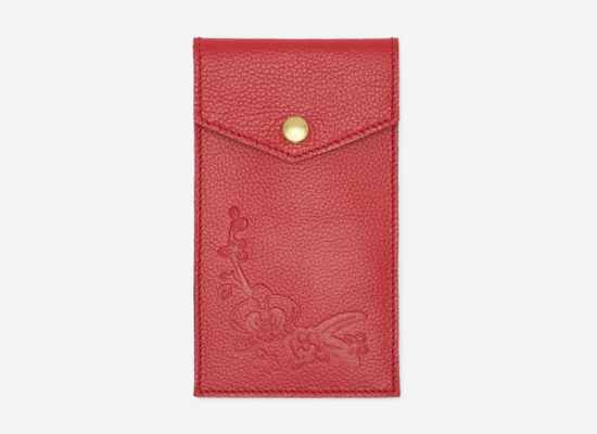 A red leather pouch with a floral motif embossed on it.