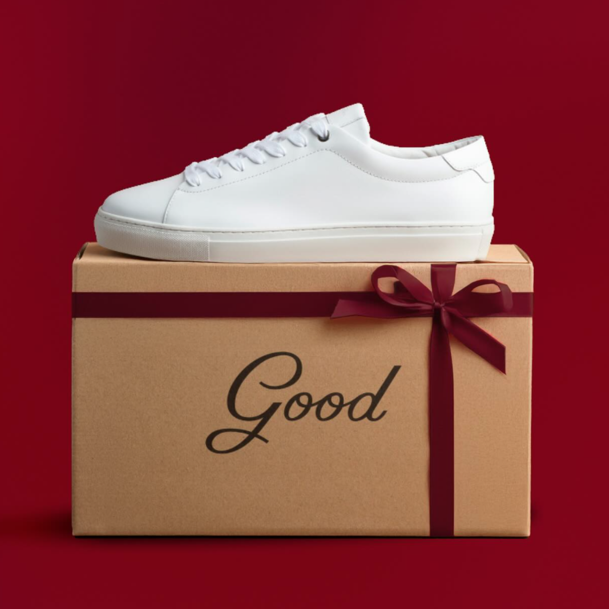 A white shoe on top of a shoe box wrapped in red ribbon.