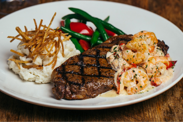 A plate of steak, shrimp and mashed potatoes.