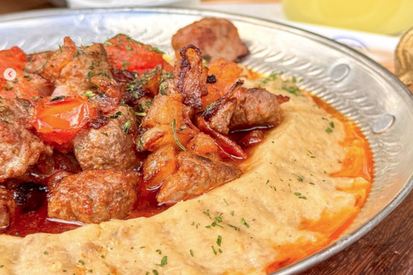 A plate of meat and hummus.