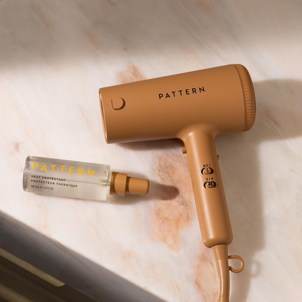 A blow dryer and a spray bottle on a counter.