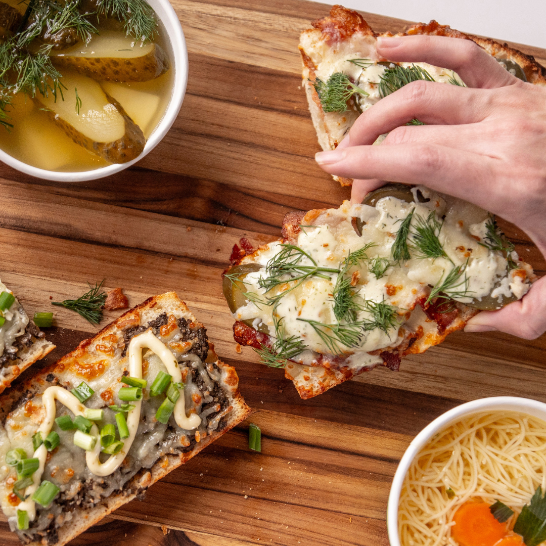 Pieces of bread with cheese, meat and garnish on top.