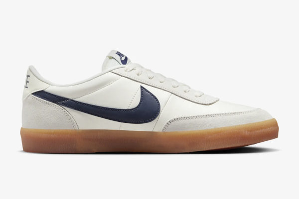 White nike sneakers with a navy swoosh logo and a gum sole.