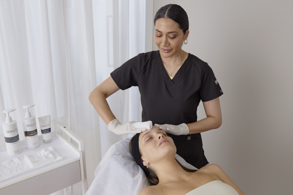 A woman performing a facial treatment on another woman.