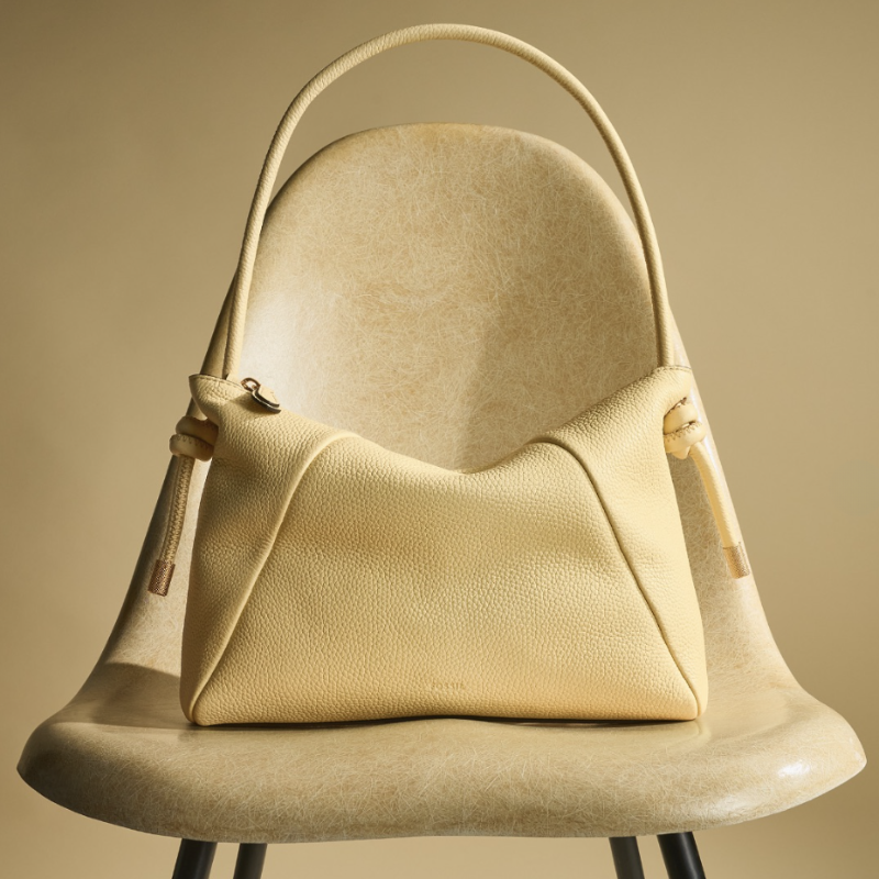 A light yellow leather hand bag on a chair.