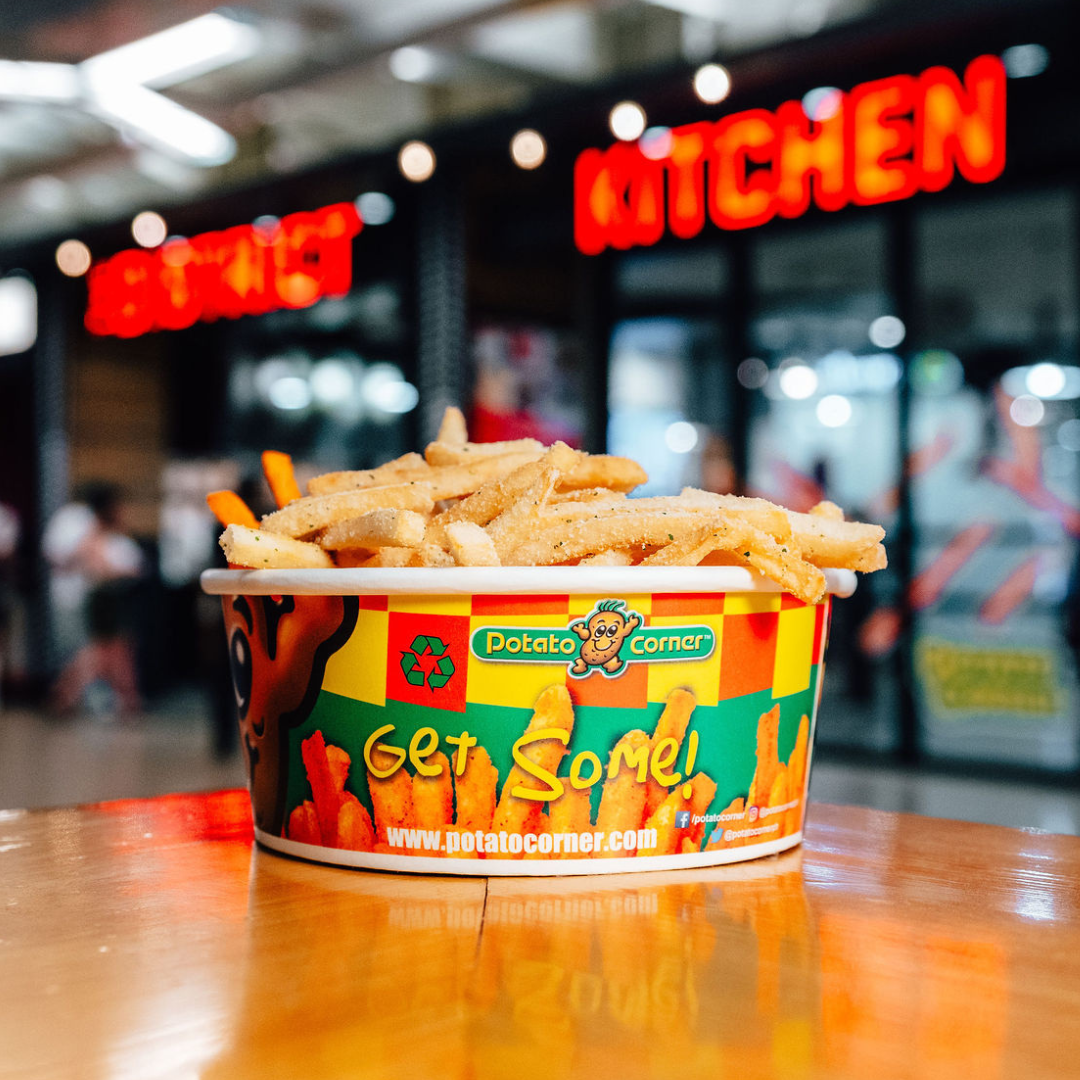 A cup of french fries on a table in front of the Food District Kitchen.