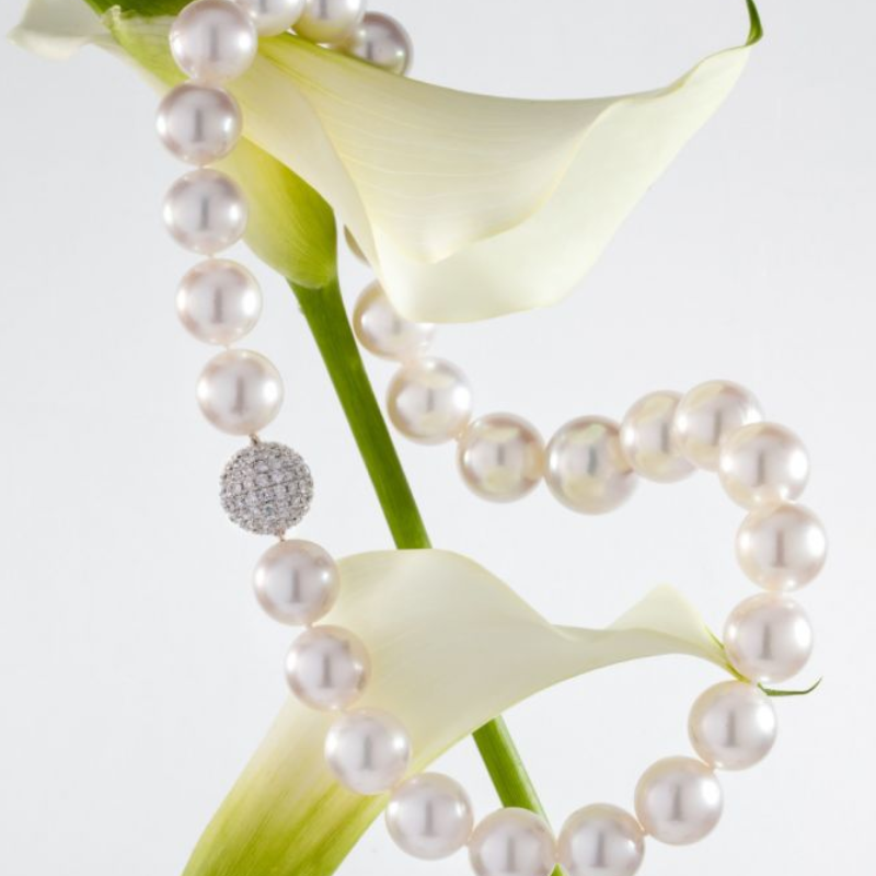 A pearl necklace and white lillies.