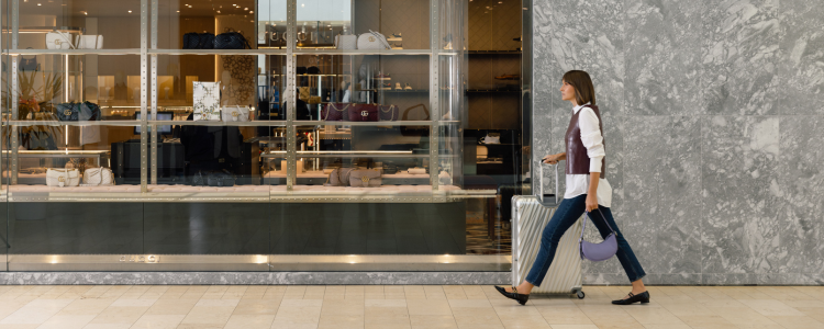 A woman walking with her luggage through a hallway at Square One