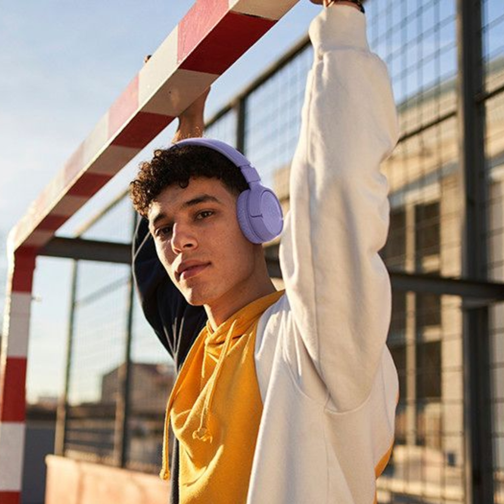 A boy wearing lilac coloured JBL headphones