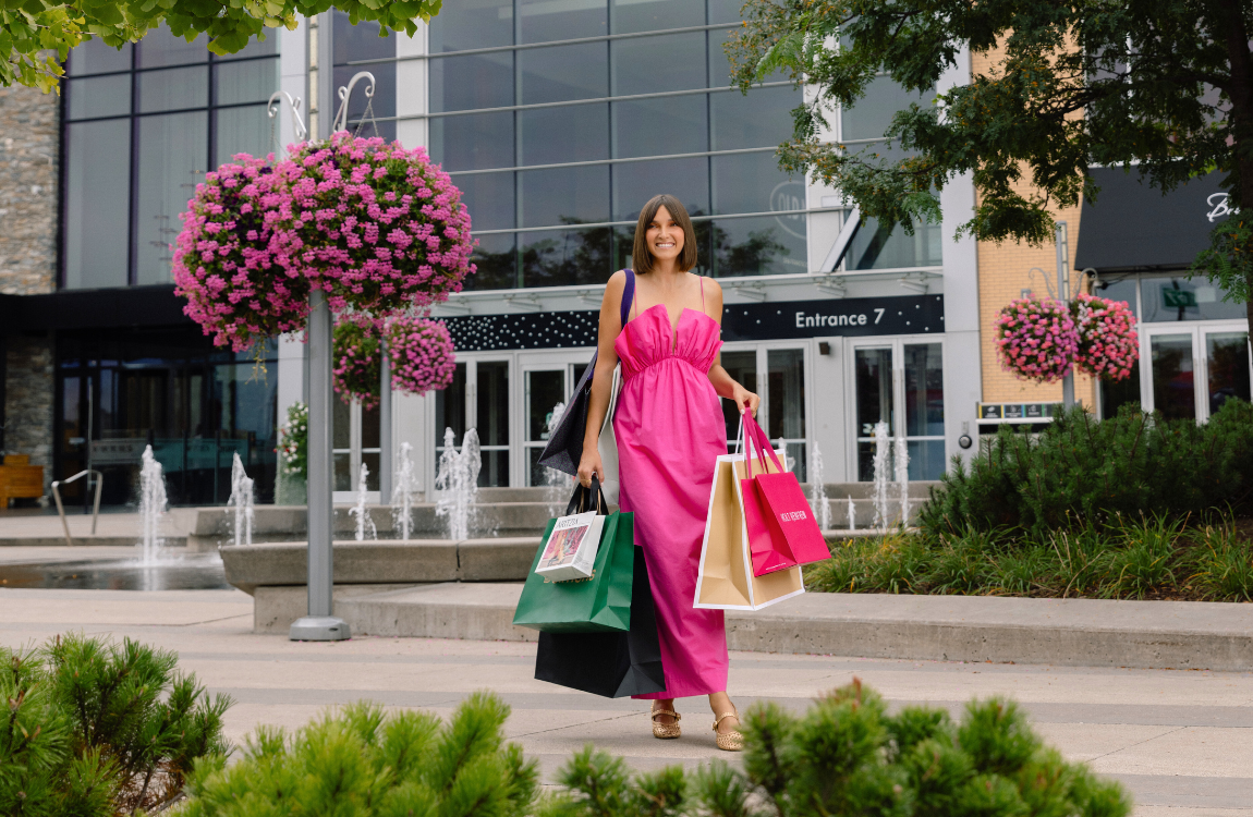 A woman in a pink dress carrying shopping bags in front of Square One's Entrance 7