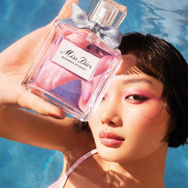 A woman holding a perfume bottle of Miss Dior